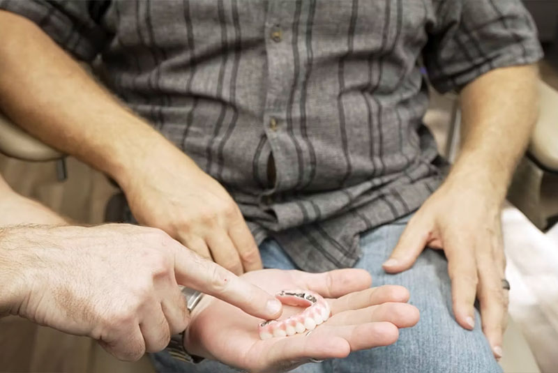 doctor showing a patient a model of a full arch of teeth
